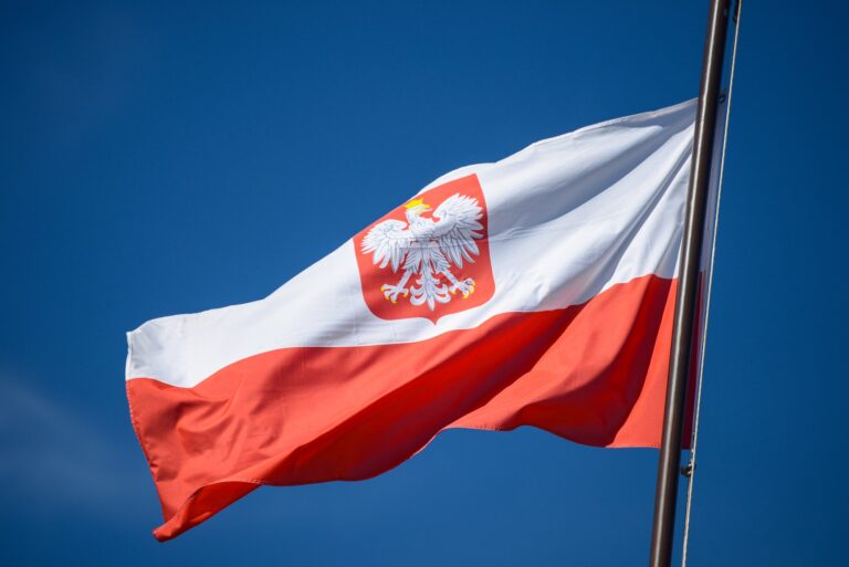 The state flag of Poland with the emblem of the Republic of Poland, on a background of blue sky, in